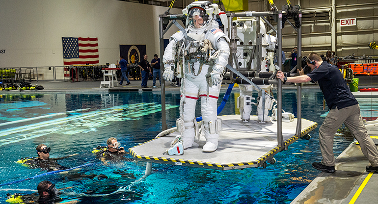 NASA astronauts are lowered into a pool containing a replica of the International Space Station at the Johnson Space Flight Center's Neutral  Buoyancy Laboratory for Extravehicular Activity training in Houston, Texas.